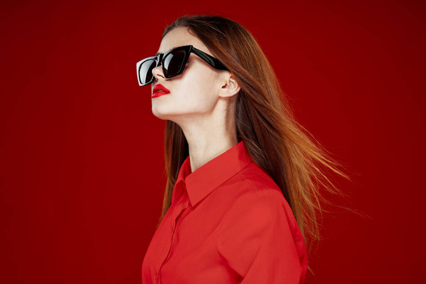 hermosa mujer usando gafas de sol camisa roja maquillaje aislado fondo - Foto, imagen