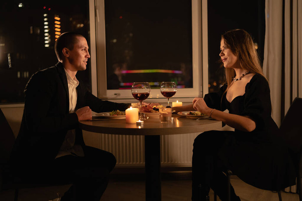 Valentine's day, romantic dinner candles with wine, couple man and woman have dinner windows and night city background, millennial love anniversary in evening restaurant, valentine's day concept - Photo, Image
