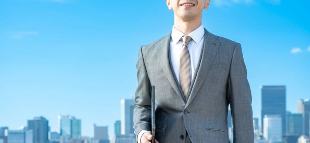 Ein Geschäftsmann vor dem Hintergrund des blauen Himmels und der Gebäude - Foto, Bild