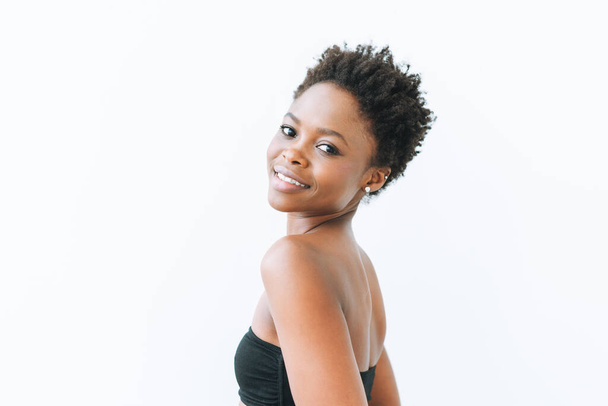 Retrato de una hermosa y sonriente mujer afroamericana de blusa negra aislada sobre fondo blanco - Foto, imagen