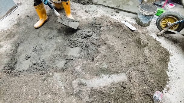 Munkás keverés cement segítségével kavicsos kövek, homok, cement, víz és egy lapát eszköz összekeverni. - Fotó, kép