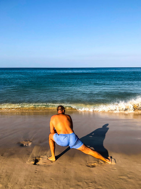 a man goes in for sports, does exercises on the seashore - Foto, Bild