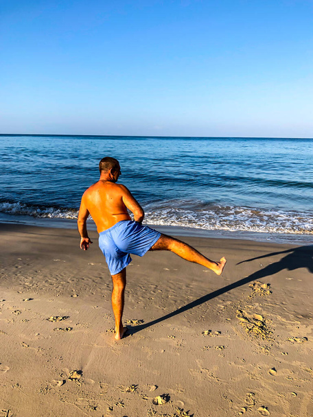 a man goes in for sports, does exercises on the seashore - Fotoğraf, Görsel