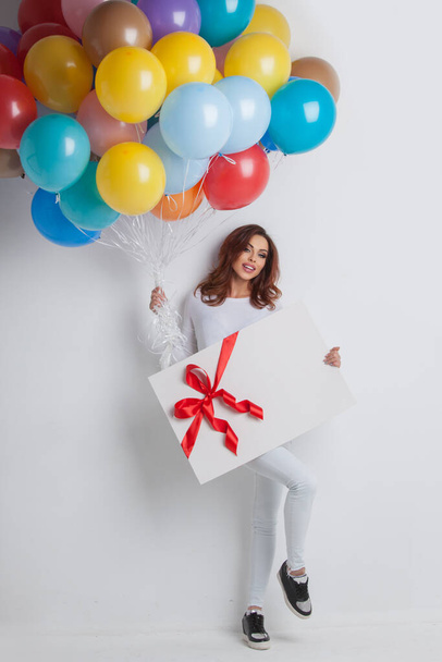 Young smiling woman with balloons and big gift box holiday gift - Foto, afbeelding