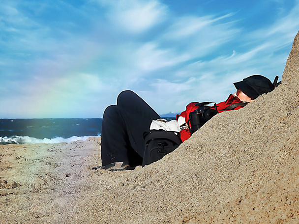 Профіль жінки з чорним капелюхом, що лежить на пляжі
 - Фото, зображення
