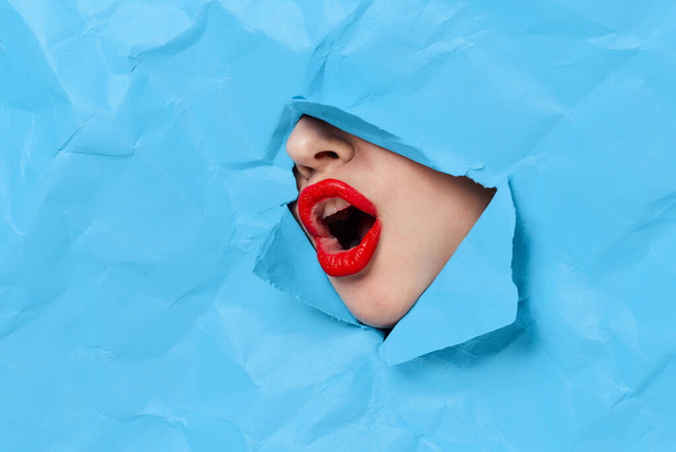 womans face breaks through blue mockup close-up - 写真・画像