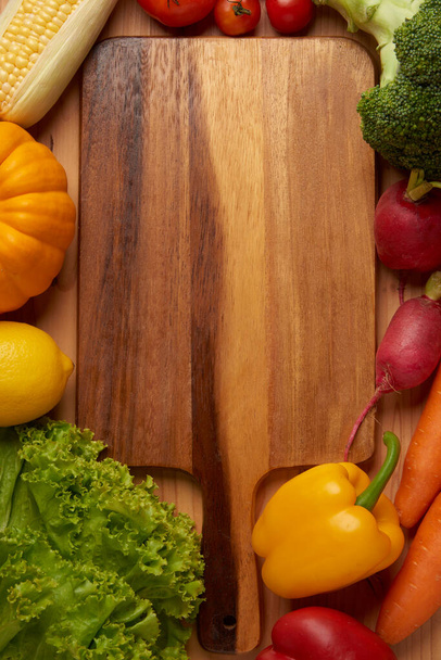 Koncepcja warzyw różne warzywa, takie jak sałaty, cytryny, dynie, kukurydza, pomidory, brokuły, buraki, papryka dzwonowa i marchewki są umieszczane na drewnianym stole. - Zdjęcie, obraz