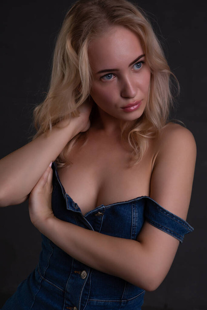 sexy charming blonde woman in an unbuttoned denim suit on a dark background - Valokuva, kuva