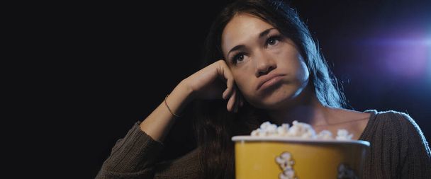 Disappointed woman watching a boring movie at the cinema - Photo, Image