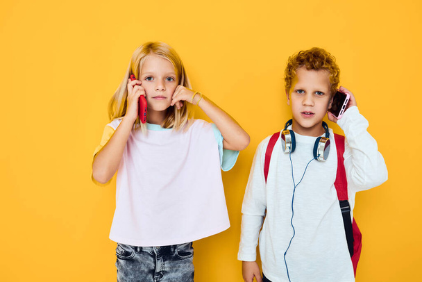 Фото двух маленьких детей девочка телефон селфи гримаса весело изолированный фон - Фото, изображение