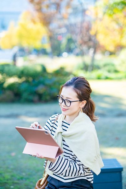 femme en vêtements décontractés en utilisant une tablette PC à l'extérieur - Photo, image
