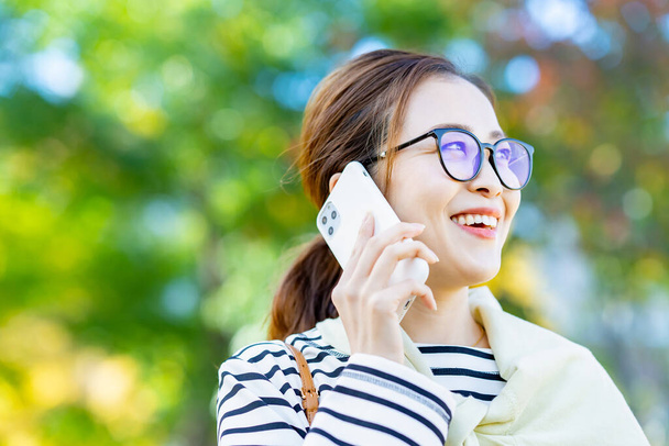 Una mujer sonriente hablando en un smartphone al aire libre - Foto, imagen