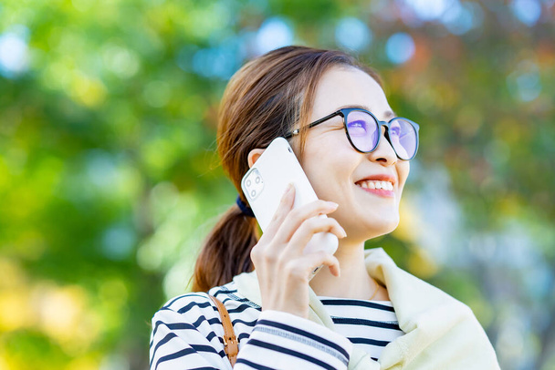 Una mujer sonriente hablando en un smartphone al aire libre - Foto, imagen