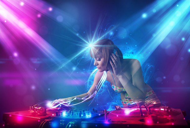 Energetic Dj girl mixing music with powerful light effects - Fotoğraf, Görsel