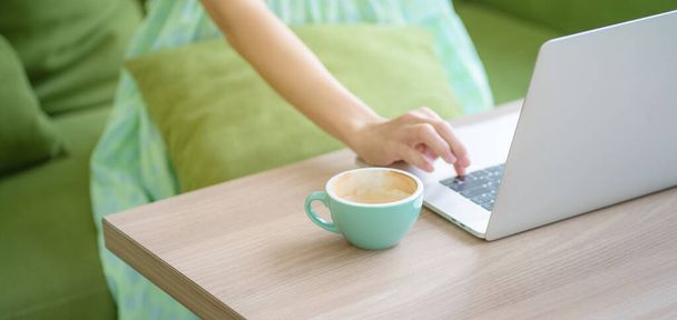 女性はカフェビジネスの女性に座ってノートパソコンドリンクラテコーヒーを使用しています - 写真・画像