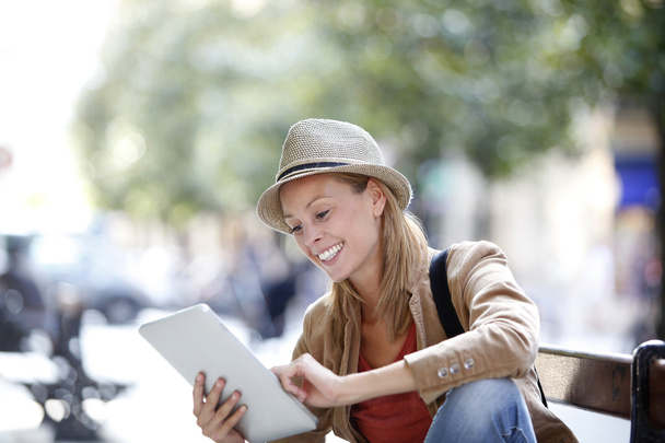 Girl using tablet sitting on bench - Zdjęcie, obraz