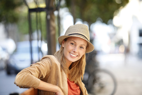 Smiling woman sitting on public bench - Zdjęcie, obraz