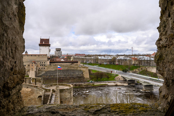 Vista desde el muro de la fortaleza hasta Narva y el puente que conecta Rusia y Estonia. Frontera estatal. Fortaleza Ivangorod. Antiguas murallas de fortaleza. Lugares históricos. - Foto, imagen