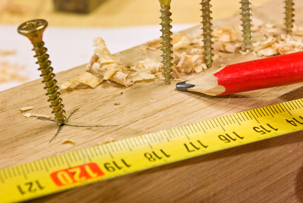Screws, pencil and measure tape on woodenk plank - Photo, Image