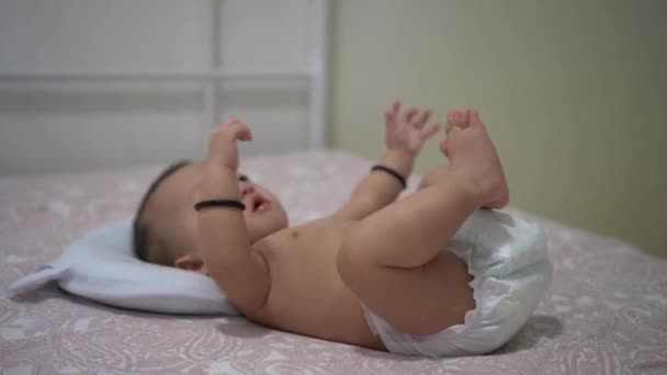 Actieve baby liggend op bed proberen om de hand en been te bewegen. Begrip babyactiviteit. - Video