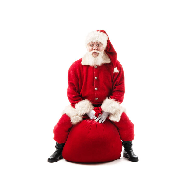 Santa Claus sitting on Christmas gift bag isolated on white background - Photo, image