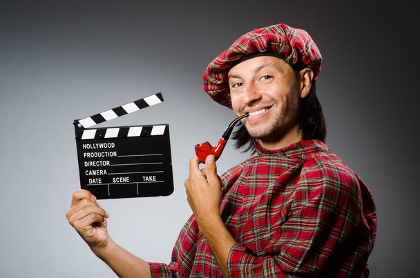 Funny scotsman with movie board and smoking pipe - Photo, Image
