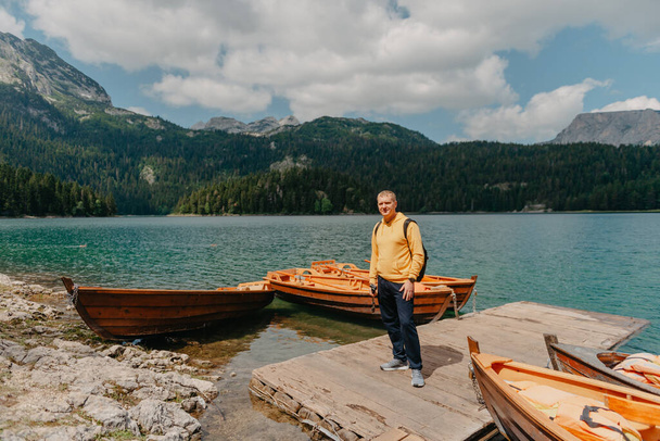 Young man looking at Black Lake, Durmitor National Park, Zabljak, Montenegro. Hipster traveler enjoying view of Black Lake - Fotó, kép