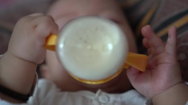 Seçici odaklanma. Bebek eli yatakta süt içmek için şişeyi tutar. - Video, Çekim