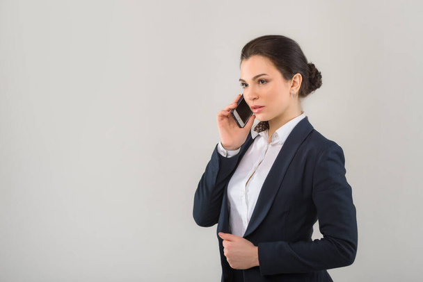 Portrét seriózní pěkné podnikatelky mluvící po telefonu v moderní kanceláři - Fotografie, Obrázek