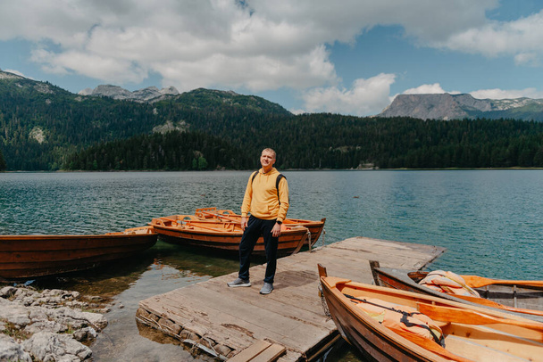 Young man looking at Black Lake, Durmitor National Park, Zabljak, Montenegro. Hipster traveler enjoying view of Black Lake - Photo, Image