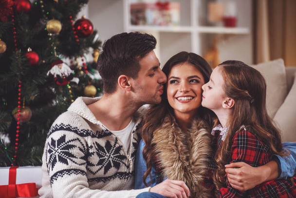 Young happy family while celebrating Christmas at home - Photo, Image