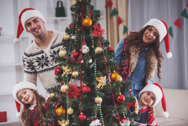 Joven familia feliz mientras se celebra la Navidad en casa
 - Foto, Imagen