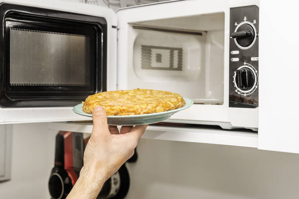 Egy kéz tartja a tányért a burgonya omlett csak ki a mikrohullámú sütő - Fotó, kép
