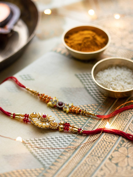 Raksha Bandhan tło z eleganckim Rakhi i ziarna ryżu na drewnianym teksturowanym tle. - Zdjęcie, obraz