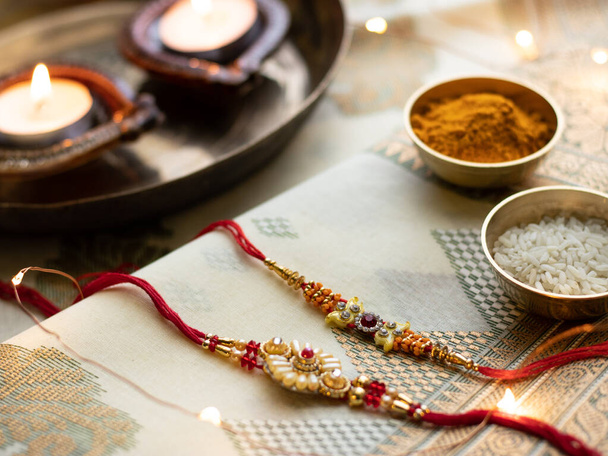 Raksha Bandhan background with an elegant Rakhi and Rice Grains on wooden textured background. - Photo, Image