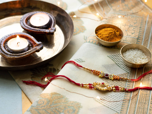 Raksha Bandhan Hintergrund mit einer eleganten Rakhi und Reiskörner auf Holz strukturierten Hintergrund. - Foto, Bild