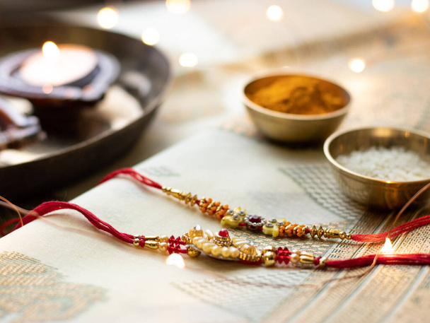 Raksha Bandhan fundo com um elegante Rakhi e grãos de arroz em fundo texturizado de madeira. - Foto, Imagem