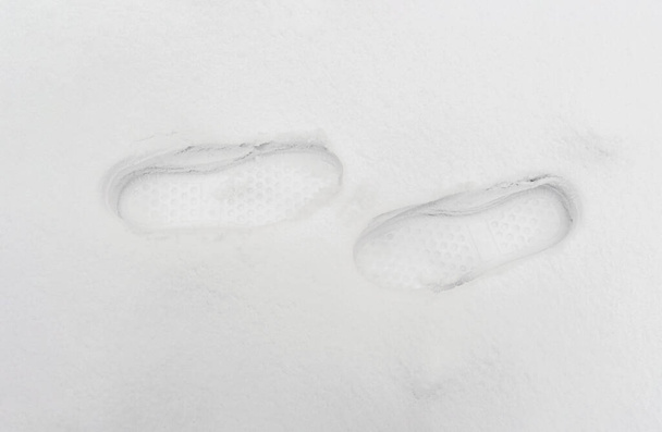 Два відбитки чоботів, пальці, що вказують один на одного, на білий сніг
. - Фото, зображення