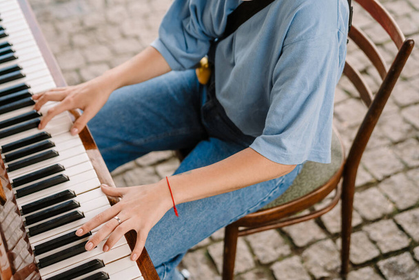 Молодая женщина играет на пианино, сидя на стуле - Фото, изображение