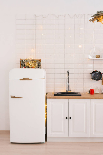 Keukengerei en decor op een wit plankje in een gezellige keuken met lichtjes. Kerstversiering - Foto, afbeelding