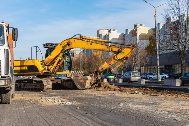 現代都市の掘削機は、道路の再建中に作業を行っています。重建設機械で街の修理 - 写真・画像