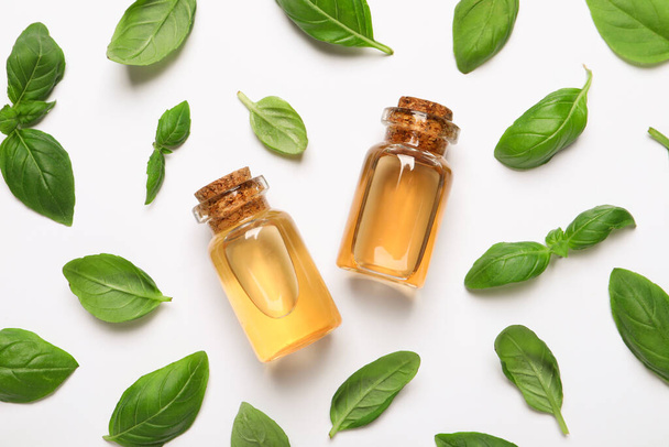 Bottles of essential basil oil and fresh leaves on white background, flat lay - Fotoğraf, Görsel