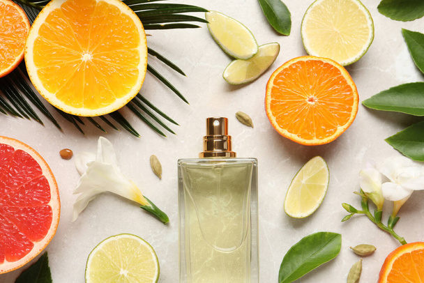 Flat lay composition with bottle of perfume and fresh citrus fruits on light marble background - Foto, immagini