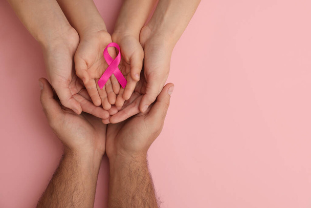 Family holding pink ribbon on color background, top view with space for text. Breast cancer awareness - Foto, Imagen