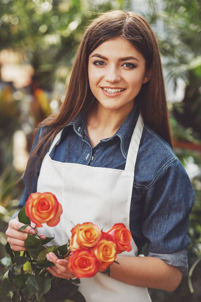 Portret van een jonge vrouwelijke bloemist in de bloemenwinkel. En kijken naar camera. - Foto, afbeelding