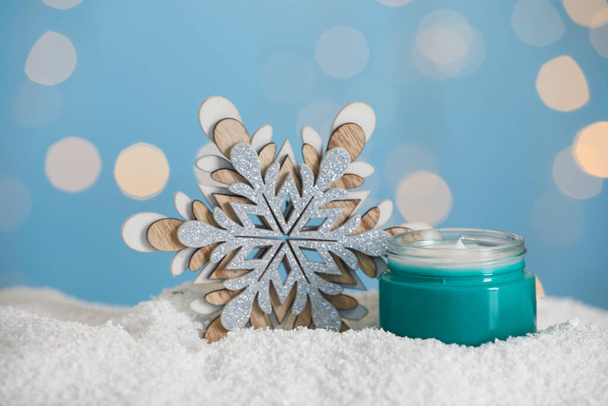 Jar of hand cream and decorative snowflake on snow against blurred lights. Winter skin care - Zdjęcie, obraz