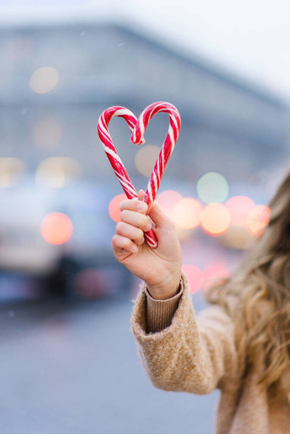 女の子の手の中に2つのキャンディーの杖で作られた心。バレンタインデーの休暇の概念 - 写真・画像