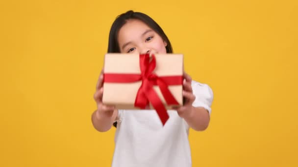 İyi tatiller. Küçük Asyalı kız kameraya hediye kutusu veriyor, kutlama yapıyor ve bayram etkinlikleri düzenliyor. - Video, Çekim