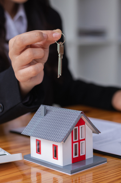Der Immobilienmakler übergibt dem Kunden die Hausschlüssel nach Unterzeichnung des Vertrages mit dem Händler. Konzept der Belieferung der Kunden mit Wohnungen nach Unterzeichnung des Kaufvertrages - Foto, Bild