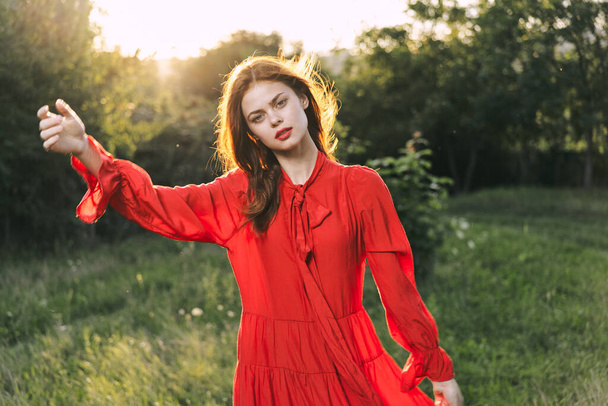 atractiva mujer en vestido rojo posando en la naturaleza hierba verde - Foto, Imagen